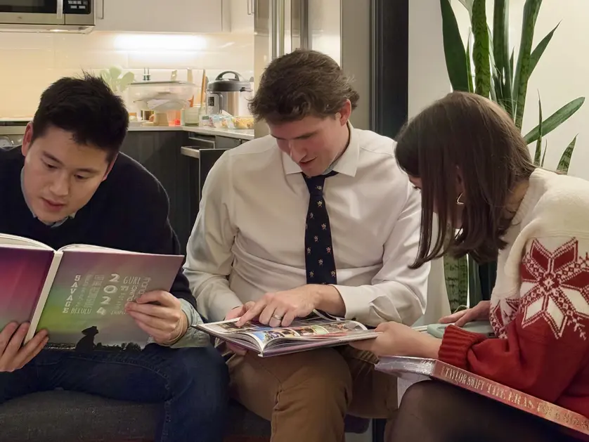 Friends gathered in a cozy living room sharing laughs and memories while flipping through their Mixbook yearbooks.