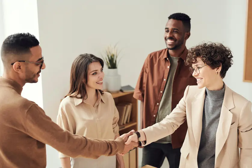Business people shaking hands or chatting over computers at a table