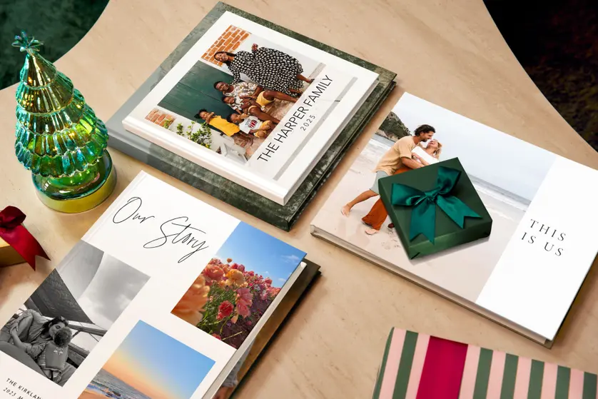 Flat lay of Mixbook family photo books styled with holiday wrapping paper and a gift box, showcasing meaningful memory-keeping gift ideas.