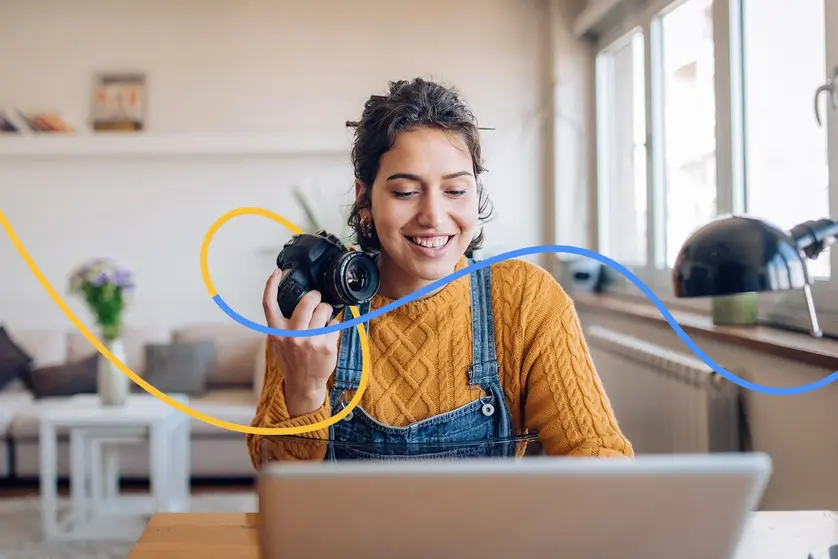 A photographer holding a camera and reviewing photos from a 30-day photo challenge on a laptop.