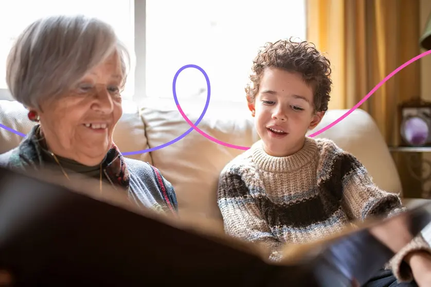 Grandmother sitting with her grandchild looks at a photo book.