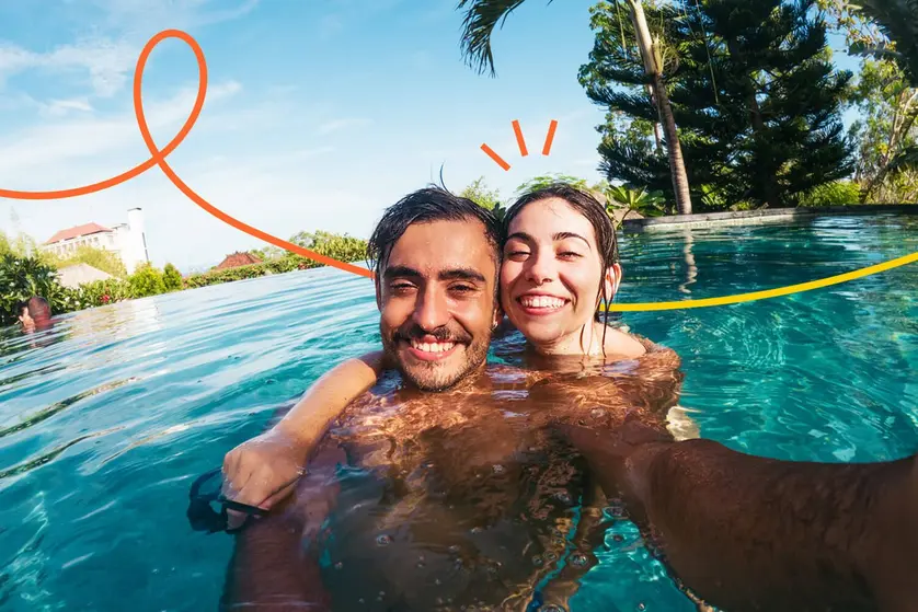 An image of a happy couple in a pool, smiling for a picture.