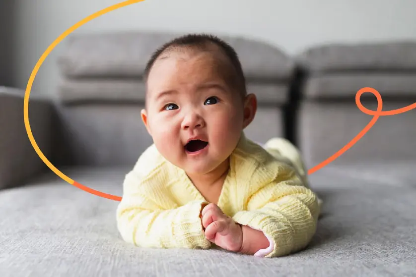An image of a smiling baby crawling on the ground.