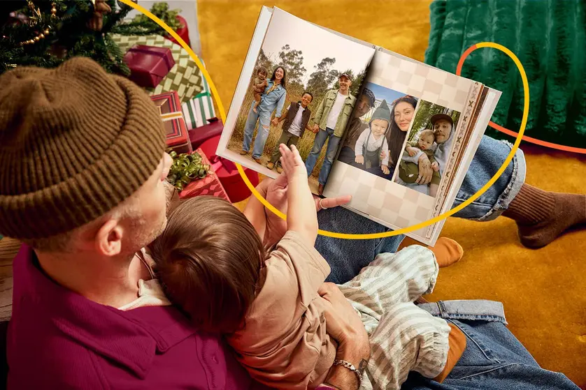 A father and child look at happy photos in a photo book.