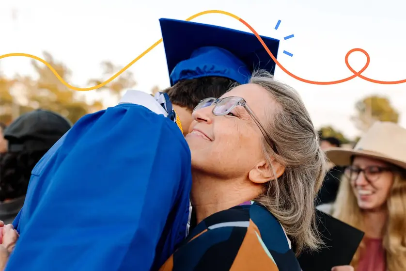 An image of a graduate hugging a family member during a graduation celebration.