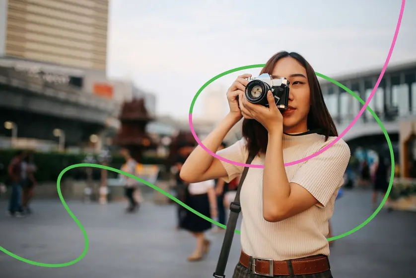 A person taking a photo on a city street using a camera.