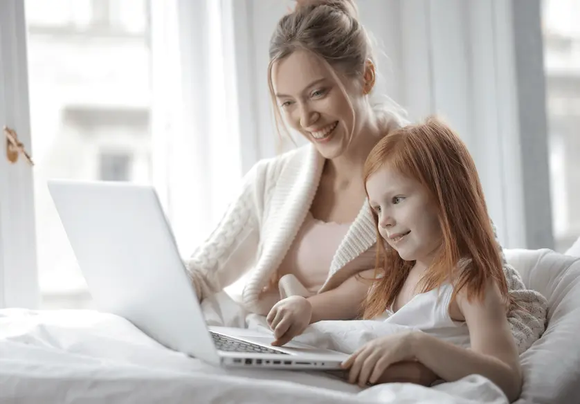 A photo of a mother and child using their laptop.