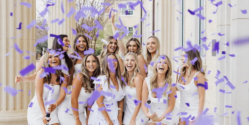 Graduates celebrating with confetti in candid outdoor moment