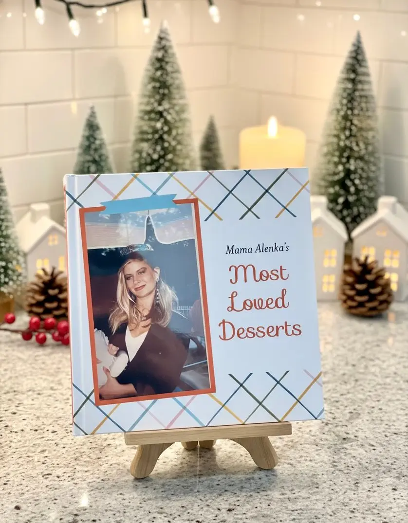 The cover of a personalized recipe photo book titled "Mama Alenka's Most Loved Desserts," featuring a photo of a young woman in a graduation cap.
