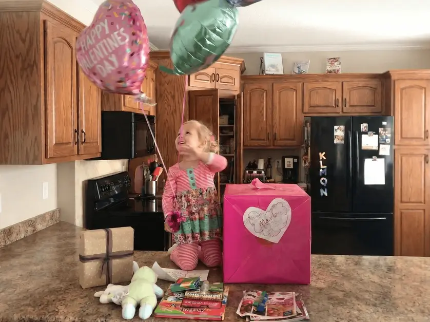 Child opening a Valentine’s themed Love Box gift with balloons and treats